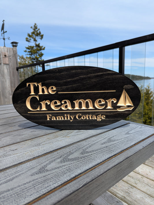 Personalized engraved wood oval sign 'The Creamer Family Cottage' with sailboat/boat graphic. Custom lake house welcome sign or marine decor plaque.