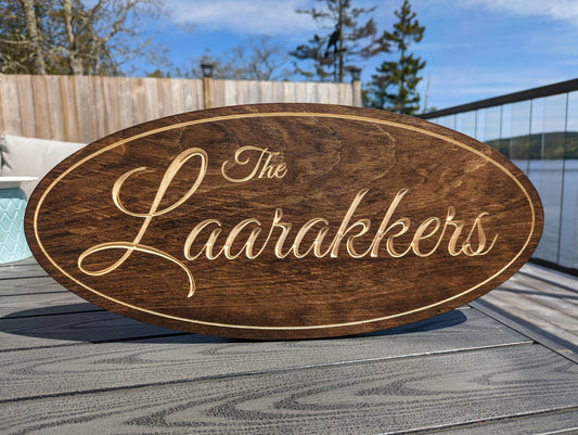 Personalized engraved wood oval sign displaying the family name 'The Laarakkers'. Custom oval plaque for home or address decor.