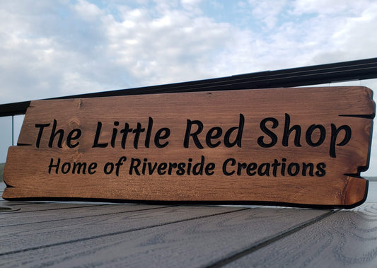 Custom engraved wood business sign with 'The Little Red Shop' and 'Home of Riverside Creations' text. Personalized shop front plaque or commercial sign for display.