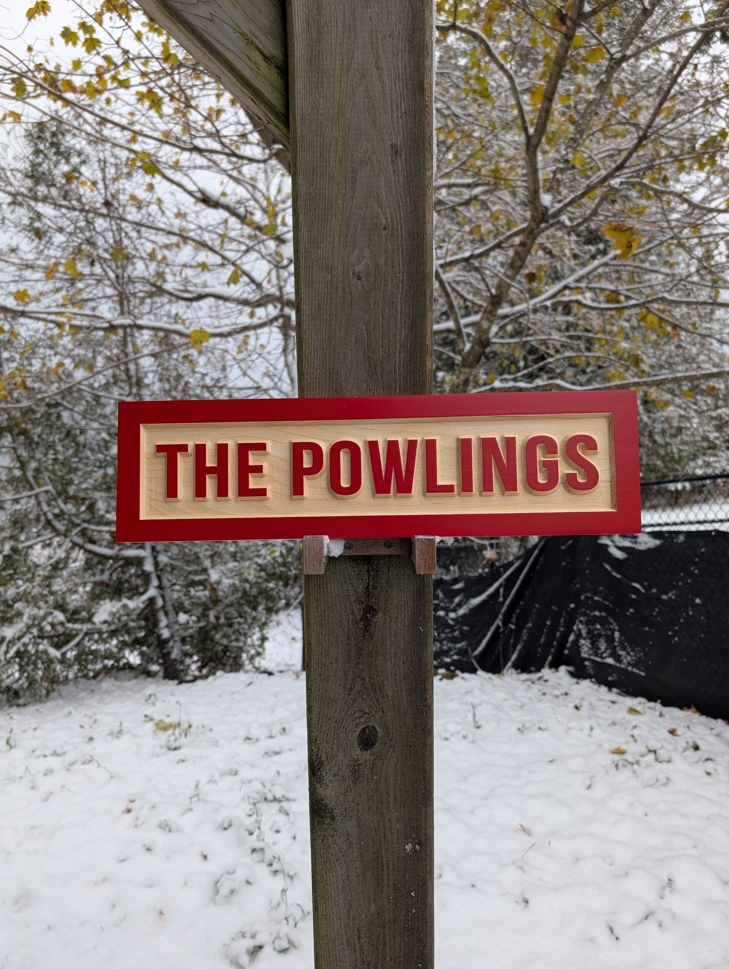 Personalized 'THE POWLINGS' family name sign mounted to a wooden pole/post in a cold, snowy setting. Durable, all-weather carved wood sign ideal for driveways and home entrances.