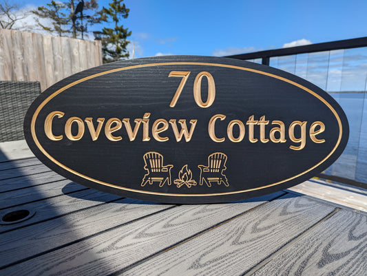 Personalized engraved wood sign '70 Coveview Cottage' featuring two chairs in front of a fire graphic. Custom cozy cottage welcome sign or fire pit decor.